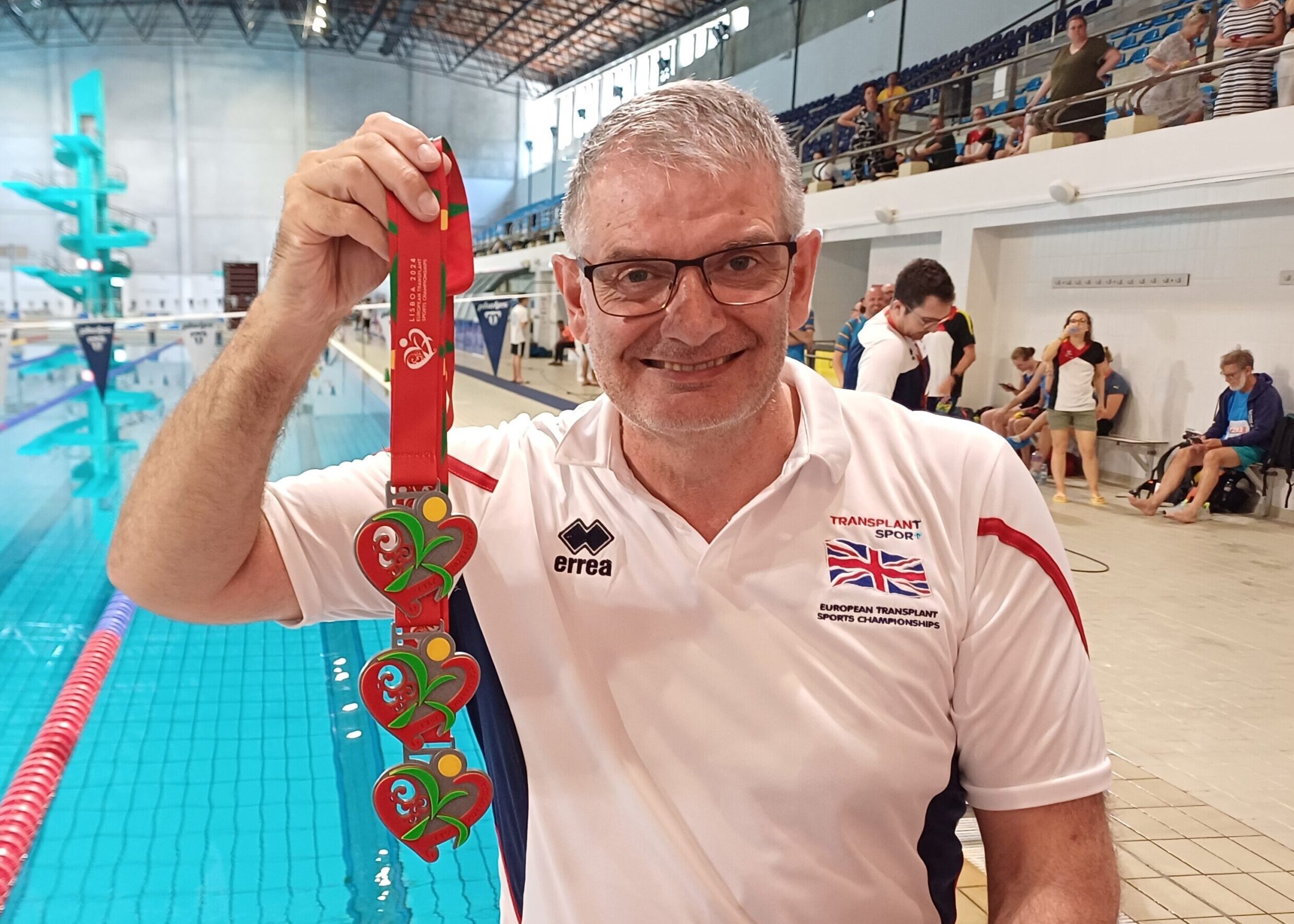 Rob Hodgkiss shows his three medals from the Championships in front of the swimming pool